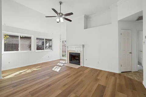 a view of a livingroom with a fireplace a ceiling fan and windows