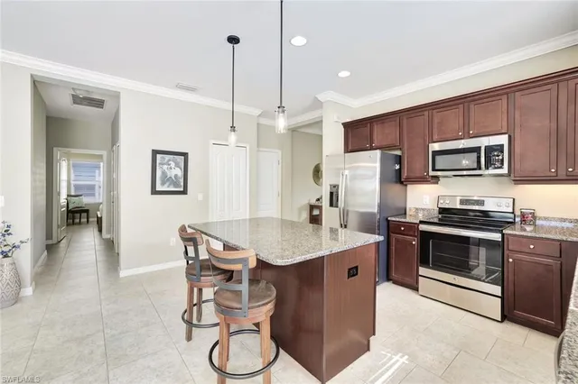 a kitchen with stainless steel appliances granite countertop a sink a stove a refrigerator cabinets and chairs