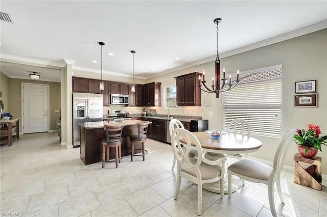 a kitchen with kitchen island a dining table chairs and white cabinets