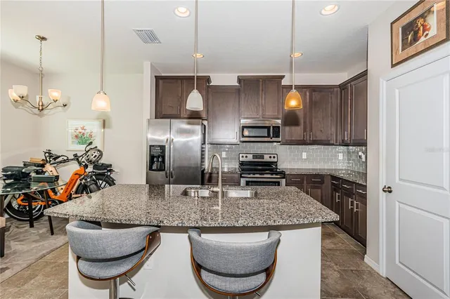a kitchen with stainless steel appliances granite countertop a sink a stove and a refrigerator