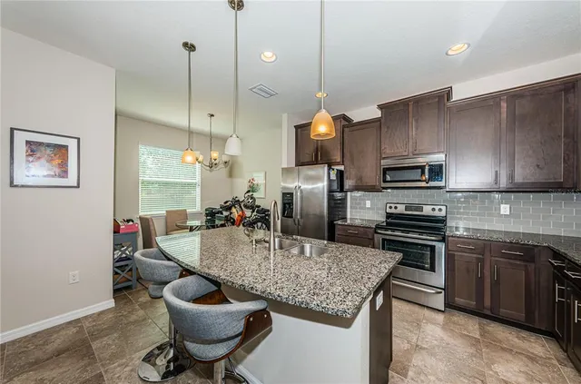 a kitchen with stainless steel appliances granite countertop a sink a stove and a wooden floors