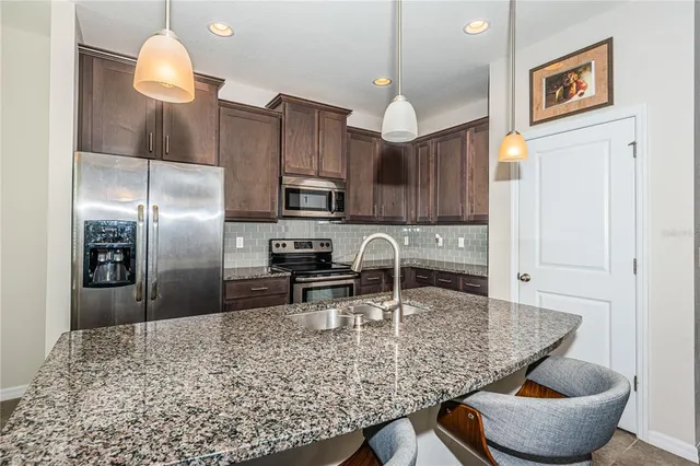 a kitchen with kitchen island granite countertop a sink cabinets and refrigerator
