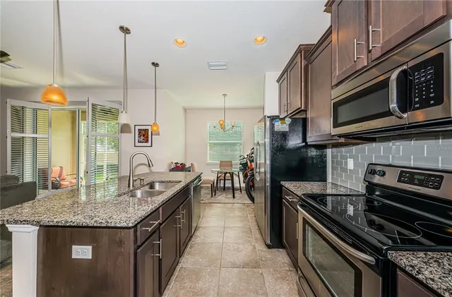 a kitchen with stainless steel appliances granite countertop a stove a sink and a microwave