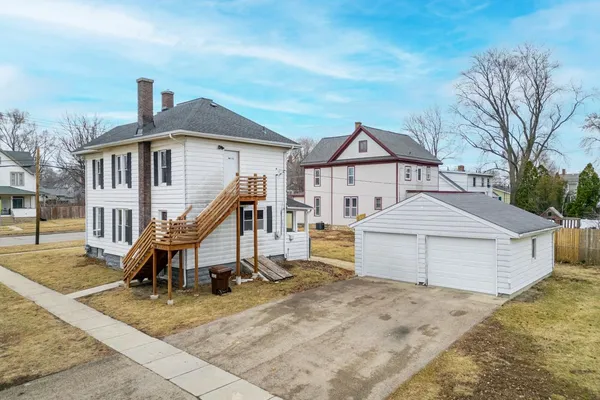 a view of a white house with wooden walls and a yard