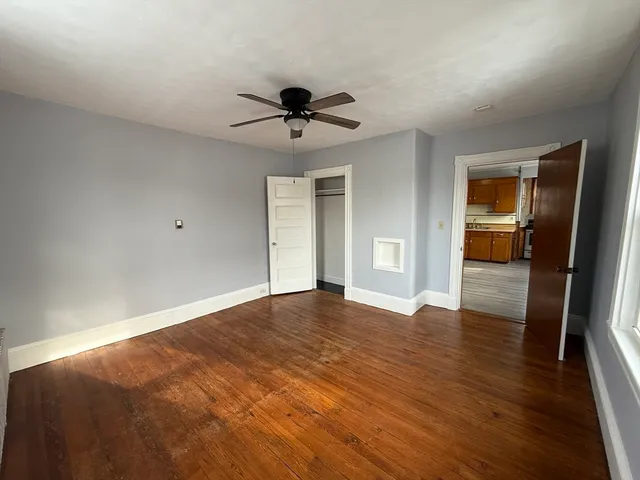 a view of empty room with wooden floor and fan