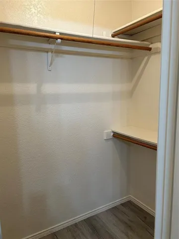 an empty room with wooden floor chandelier fan and window