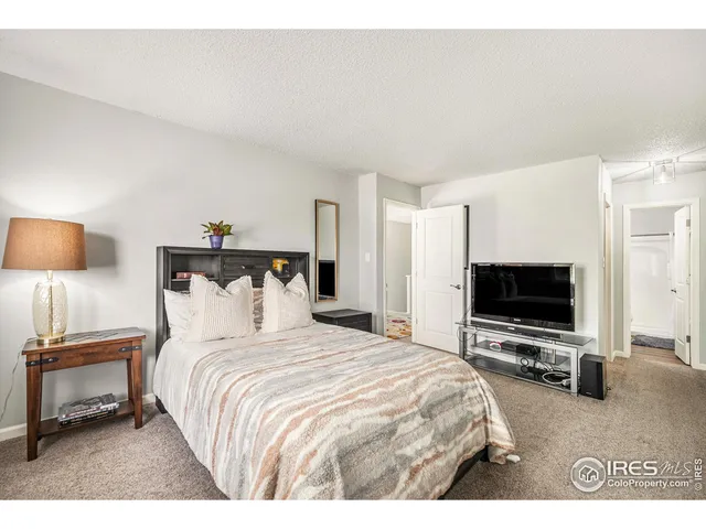 a bedroom with a bed and a flat tv screen on wall