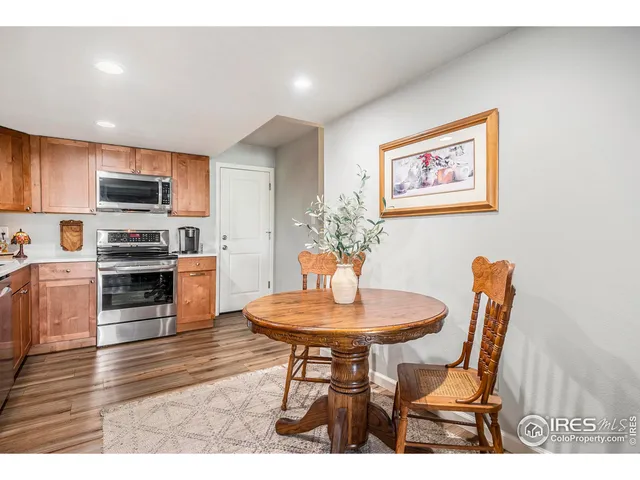 a kitchen with stainless steel appliances kitchen island granite countertop a dining table chairs and a refrigerator