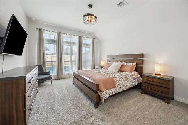 a spacious bedroom with a bed and a flat screen tv