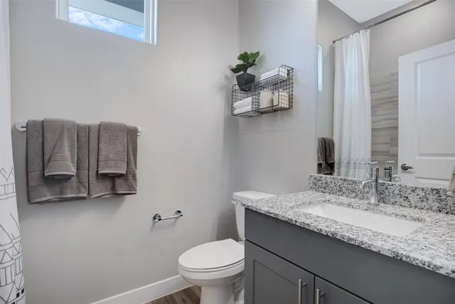 a bathroom with a granite countertop sink a toilet and mirror