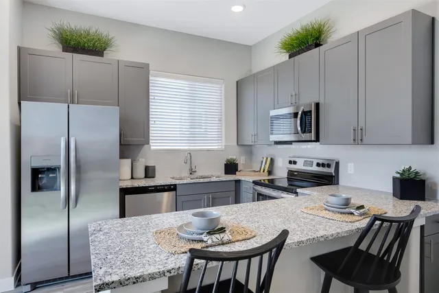 a kitchen with stainless steel appliances granite countertop a refrigerator a stove a sink a dining table and chairs