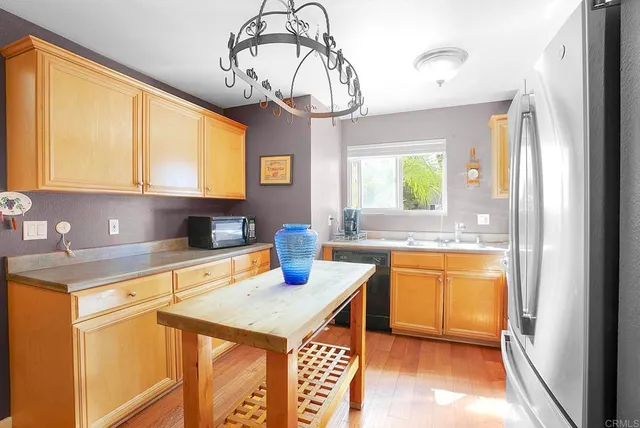a kitchen with stainless steel appliances granite countertop a sink a stove cabinets dining table and chairs