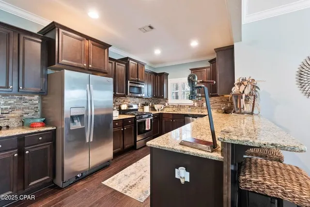 a kitchen with stainless steel appliances granite countertop a refrigerator a stove and a sink