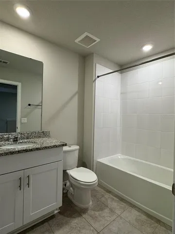 a bathroom with a granite countertop sink a toilet and shower