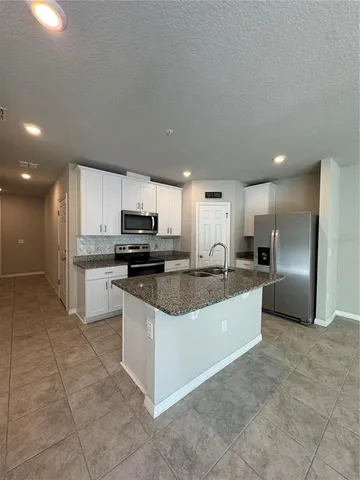 a large kitchen with stainless steel appliances granite countertop a sink a stove a microwave and a refrigerator