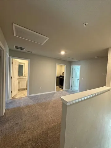 a view of an empty room with window and kitchen