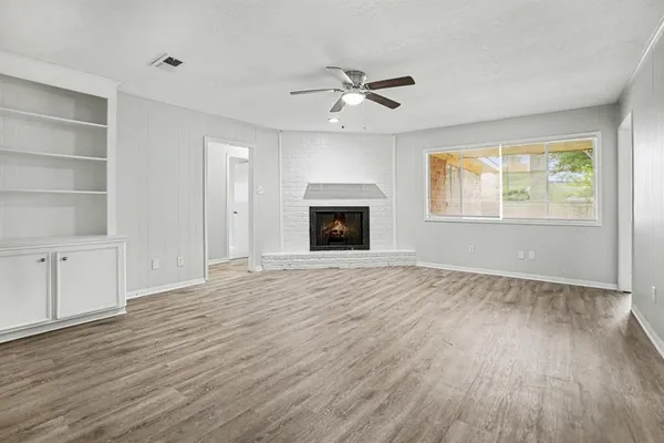 a view of an empty room with a window and wooden floor