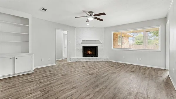 an empty room with windows fireplace and wooden floor