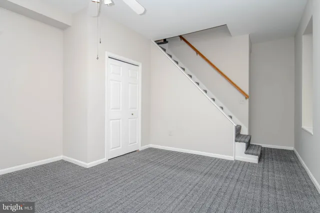 a view of an empty room with wooden floor and stairs