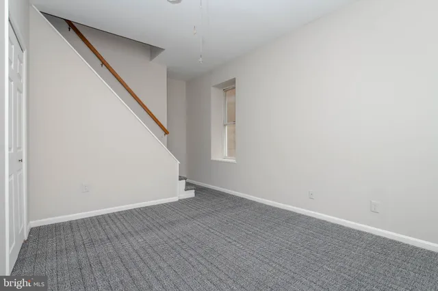 a view of an empty room with wooden floor and white walls