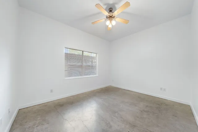an empty room with a window and a fan