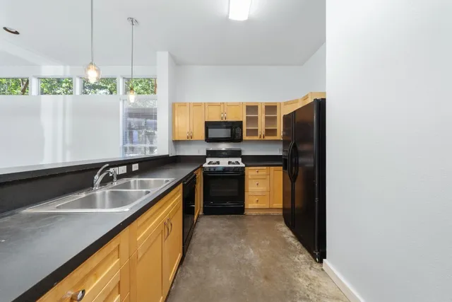 a kitchen with granite countertop a sink stove and refrigerator
