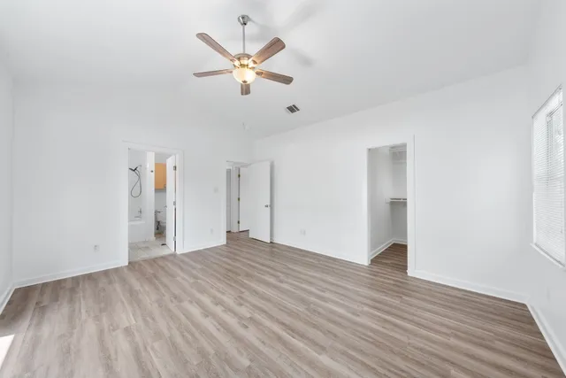 an empty room with wooden floor and ceiling fan