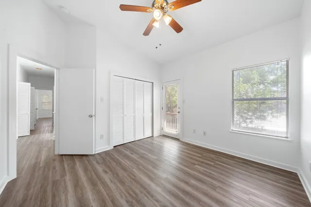 a view of an empty room with wooden floor and a window