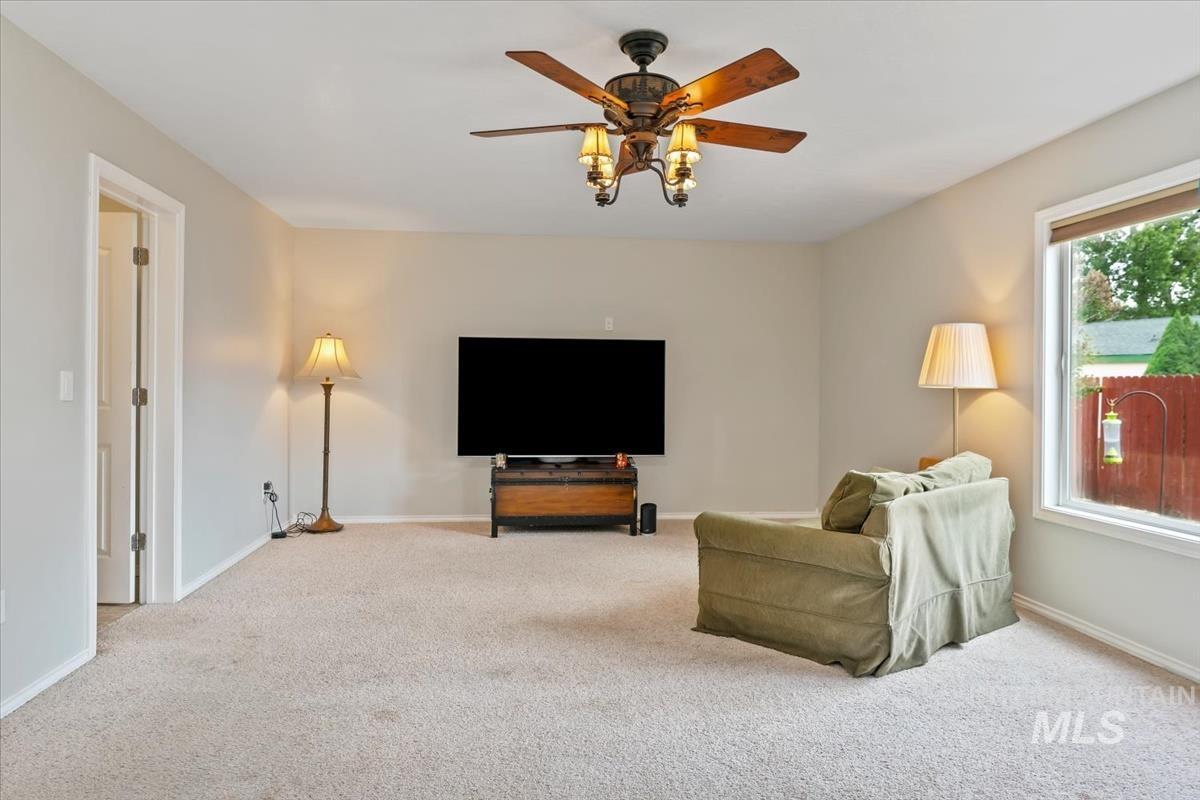 80 Cobblestone Court Middleton, ID 83644 - Photo 14 of 48 Spacious room featuring neutral wall paint, light-colored carpet, a ceiling fan with integrated lighting, and a large window