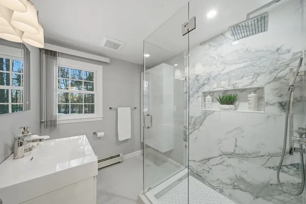 a bathroom with a sink shower and a mirror