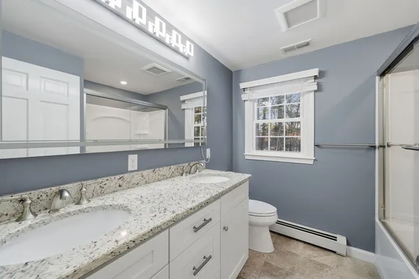 a bathroom with a granite countertop sink a toilet and a window