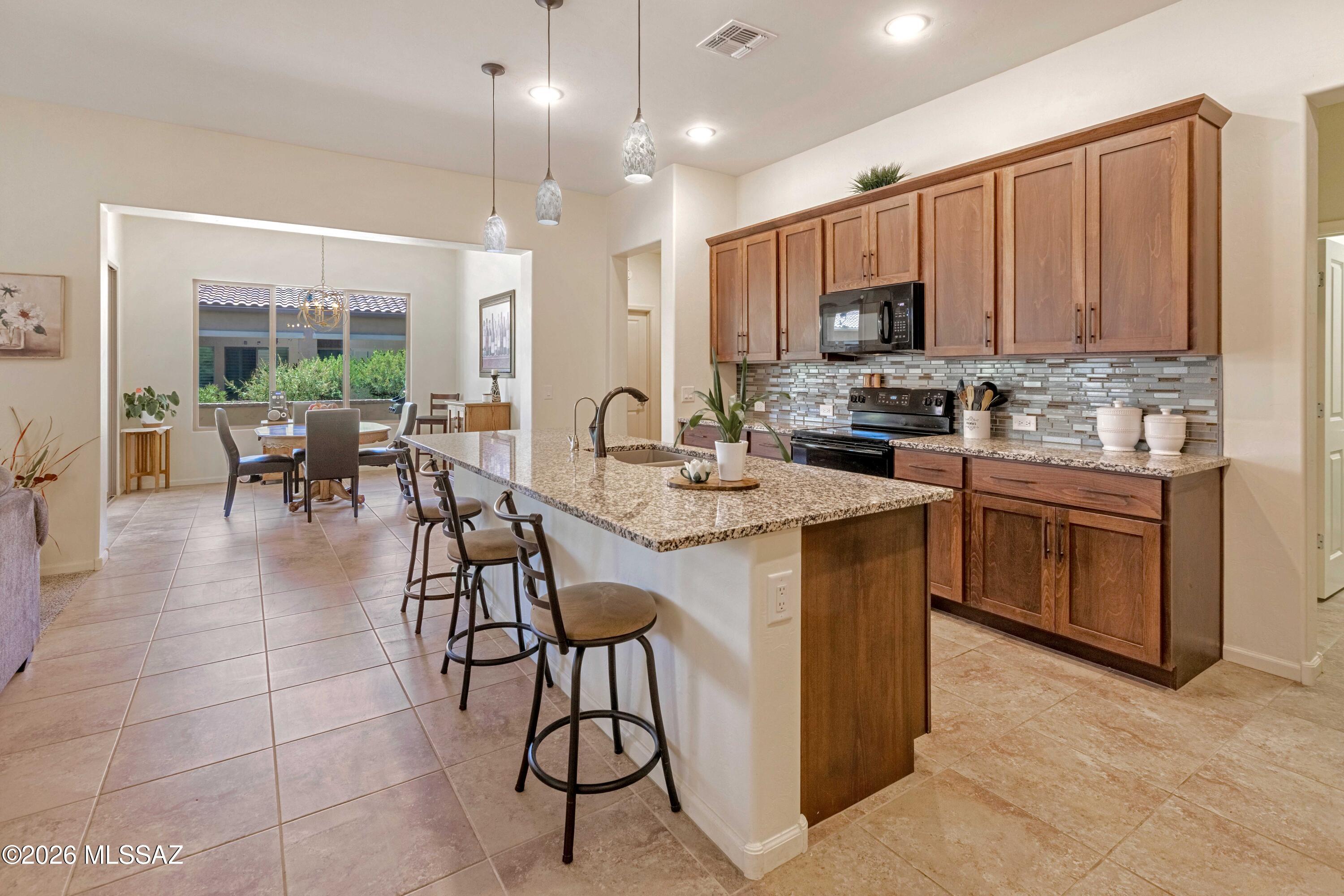 61193 East Shale Road Oracle, AZ 85623 - Photo 7 of 50 a kitchen with stainless steel appliances a stove a sink a oven a dining table and chairs