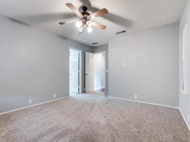 a view of an empty room with a chandelier fan