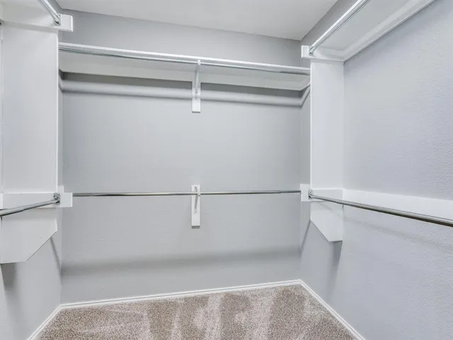 a view of walk in closet with empty racks