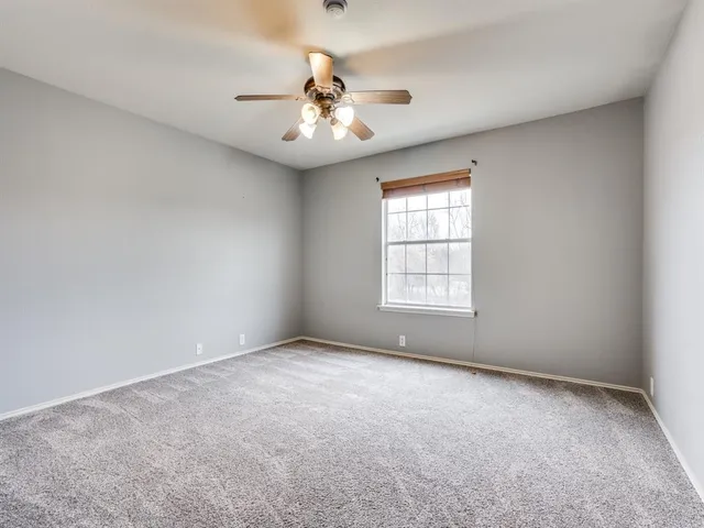 an empty room with windows and chandelier fan