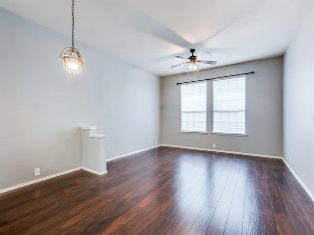a view of an empty room with wooden floor ceiling fan and a window