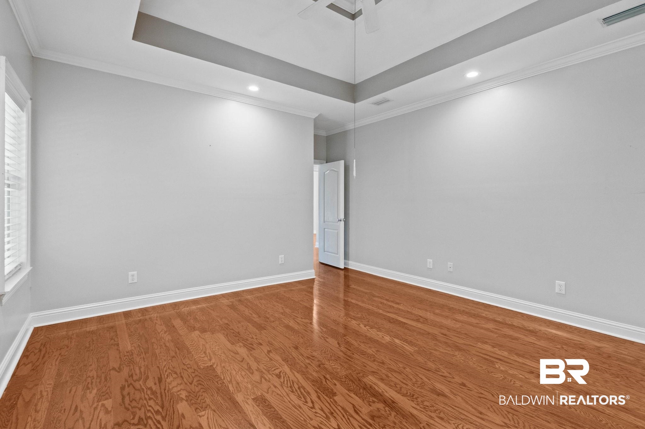 3176 Cedar Court Mobile, AL 36619 - Photo 15 of 33 Hardwood flooring throughout featuring a tray ceiling with recessed lighting and crown molding