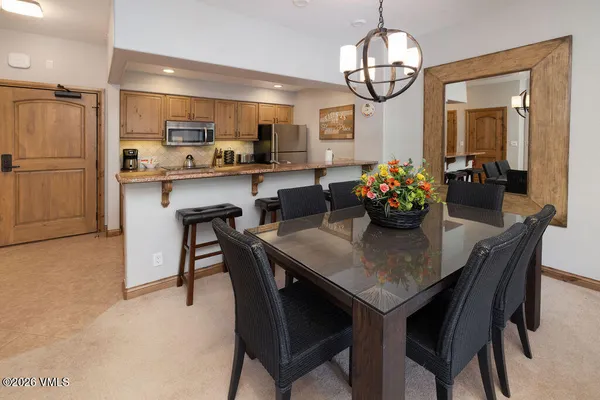 a dining room filled chandelier and kitchen view
