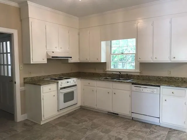 a kitchen with granite countertop white cabinets and white appliances