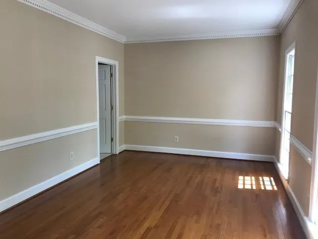 a view of an empty room with wooden floor and window