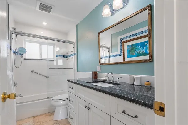 a bathroom with a granite countertop sink a toilet and a mirror