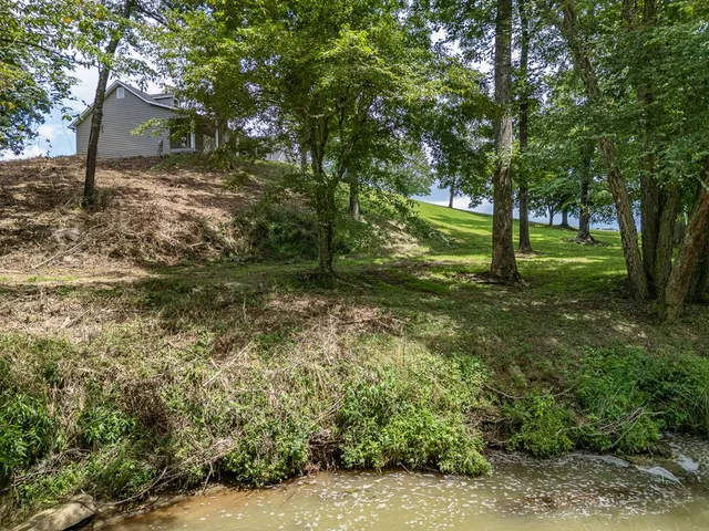 a view of a house with a big yard and large trees