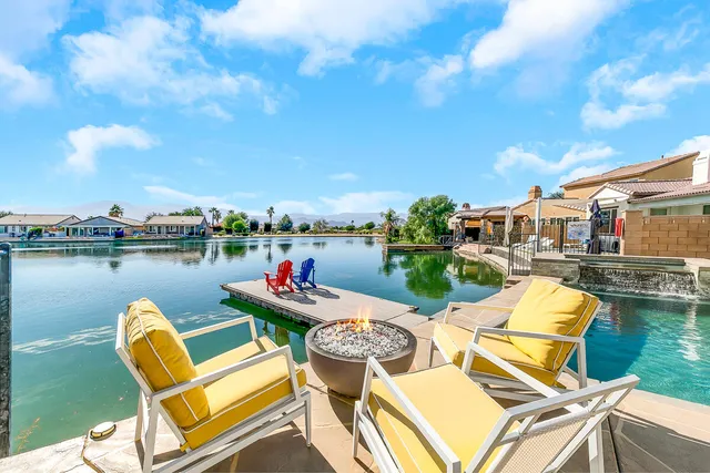 a view of a lake with couches chairs and swimming pool