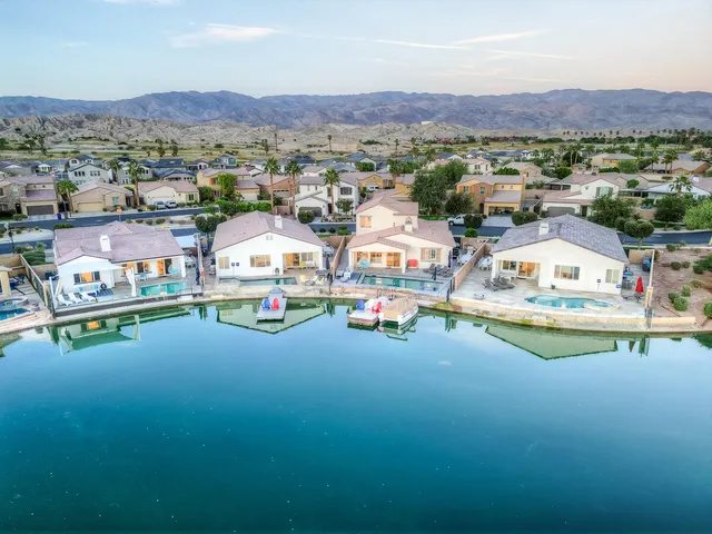 an aerial view of residential houses with outdoor space and lakeside