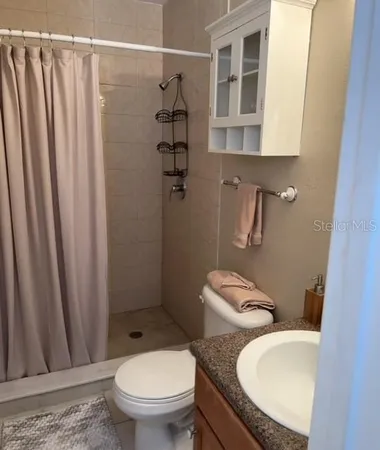 a bathroom with a granite countertop toilet and a sink