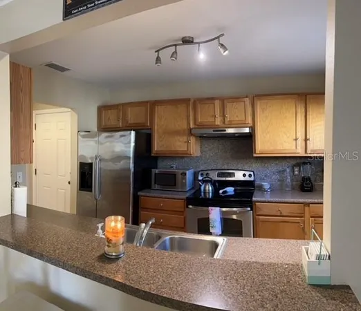 a kitchen with stainless steel appliances granite countertop a sink a stove and a refrigerator