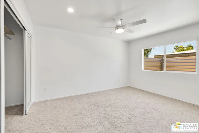 an empty room with windows and fan