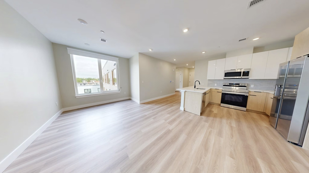 an open kitchen with wooden floor and stainless steel appliances