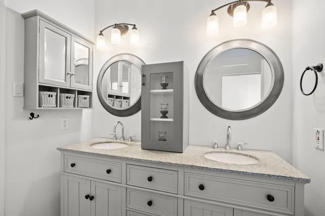 a bathroom with a granite countertop double vanity sink and a mirror