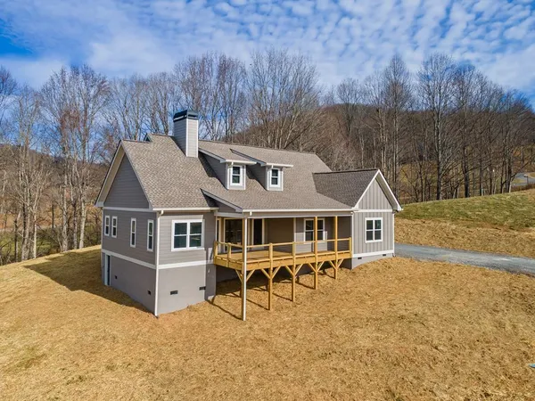 an aerial view of a house with wooden deck and furniture